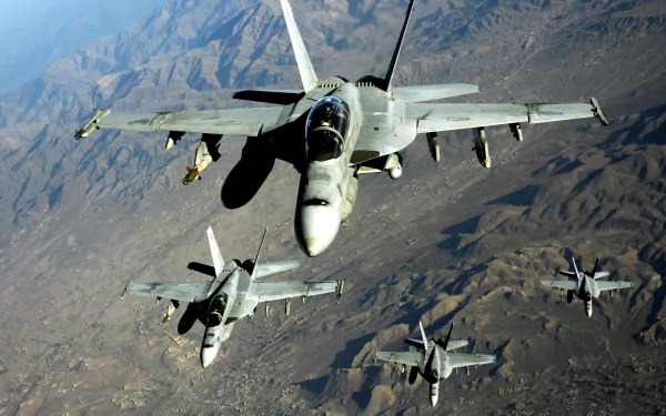Four McDonnell Douglas F/A-18 Hornets fly in formation over mountainous terrain, showcasing the power and agility of these military aircraft. A dynamic HD desktop wallpaper.