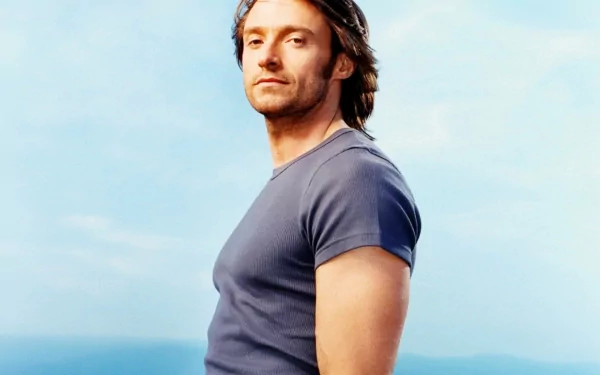 A striking HD desktop wallpaper featuring celebrity Hugh Jackman, showcasing him in profile against a serene blue sky, highlighting his confident demeanor and tousled hair.