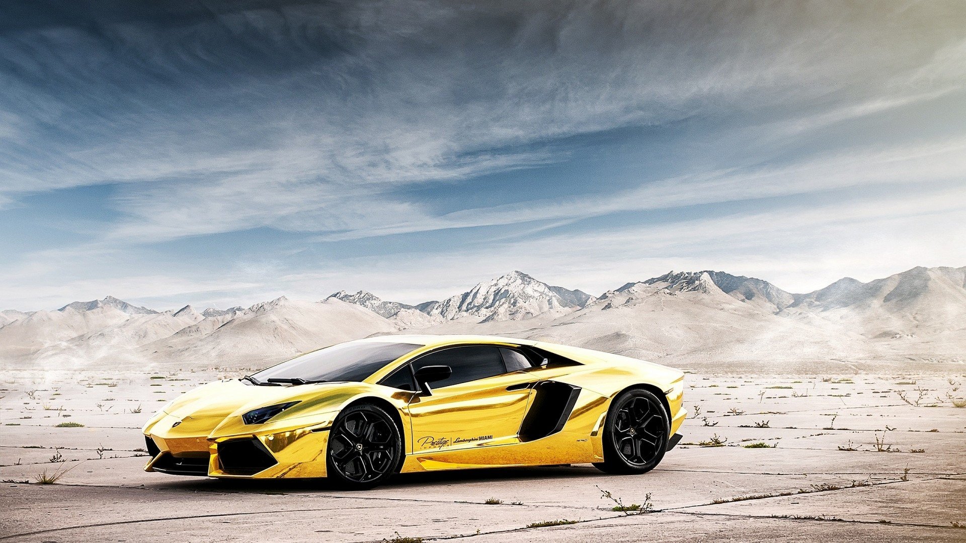 HD PC desktop wallpaper featuring a sleek yellow Lamborghini Aventador parked on a cracked desert landscape under a cloudy sky.