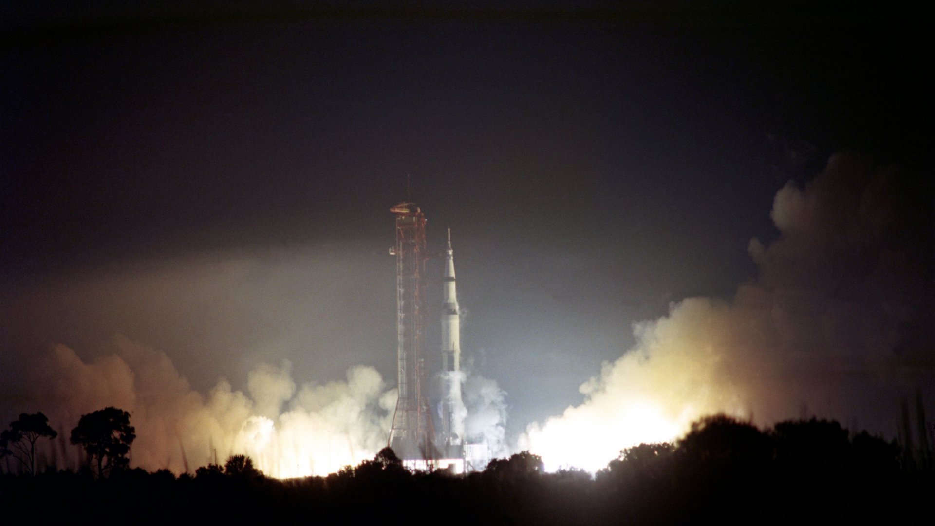 HD NASA desktop wallpaper capturing a dramatic nighttime rocket launch with bright flames and smoke illuminating the sky, showcasing iconic man-made space technology.