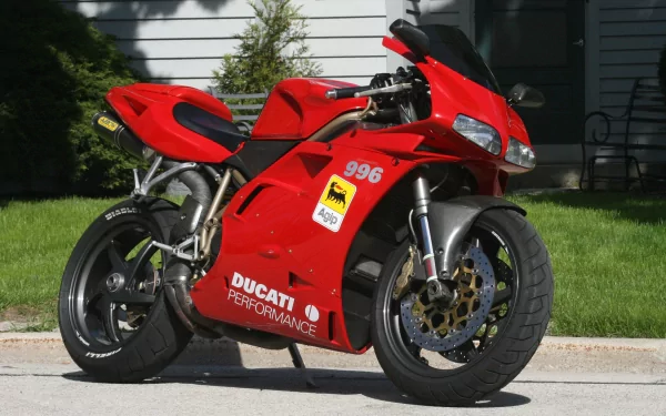 Red Ducati sport motorcycle parked on a sunlit driveway, captured as a 2K Quad HD PC desktop wallpaper and background.