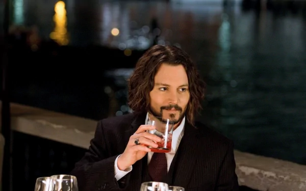A high-definition desktop wallpaper featuring Johnny Depp, elegantly dressed and holding a drink, set against a blurred background of shimmering lights and water.