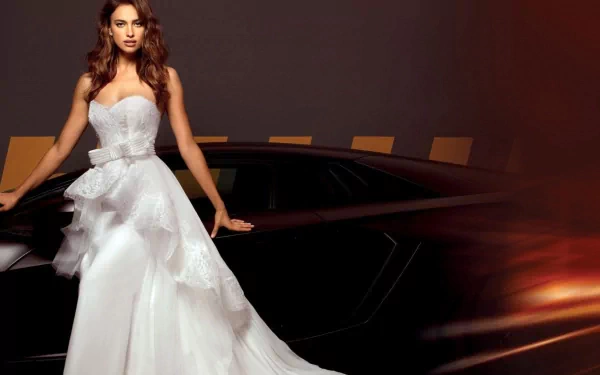 HD PC desktop wallpaper featuring celebrity Irina Shayk in a flowing white gown beside a sleek black sports car against a dark, moody background.