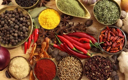 A vibrant assortment of herbs and spices displayed in bowls, featuring colorful chili peppers, dried herbs, and various spices, creating an enticing food-themed PC desktop wallpaper.