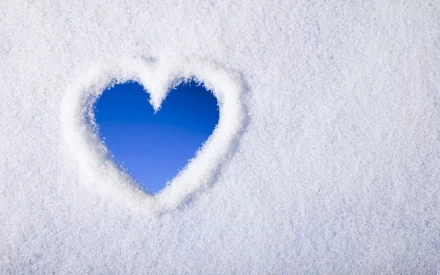 A heart shape carved into snow reveals a vibrant blue center, creating a striking contrast. This artistic image serves as an HD desktop wallpaper and background.