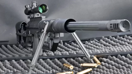 HD desktop wallpaper featuring a sniper rifle with a scope, set against a foam-lined background, with several bullet casings scattered in the foreground.