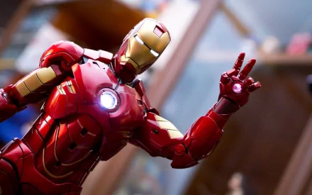 HD wallpaper featuring a highly detailed Iron Man figurine in a dynamic pose, with a glowing chest arc reactor and repulsor. The background is slightly blurred, emphasizing the figurine’s vivid colors.