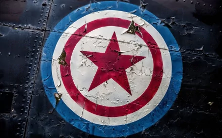 HD desktop wallpaper featuring a distressed Captain America shield logo on a dark, textured background. The shield has a red star in the center, encircled by red, white, and blue rings.
