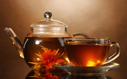 A beautifully arranged teapot with blooming tea and a cup on a saucer, set against a warm, ambient background, creating an inviting atmosphere for tea lovers.