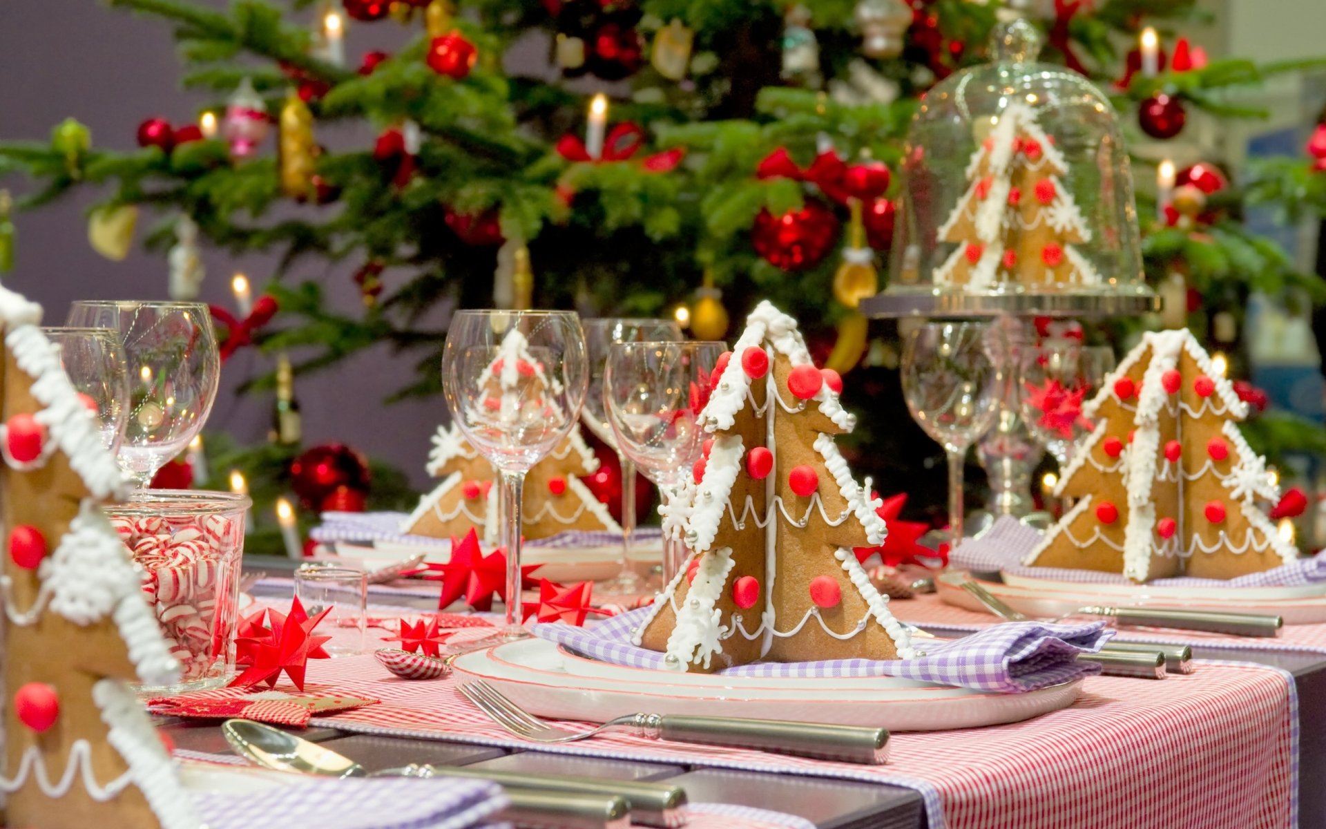 HD holiday wallpaper featuring a festive Christmas table setting with glassware, gingerbread houses, and candy canes in front of a decorated Christmas tree.