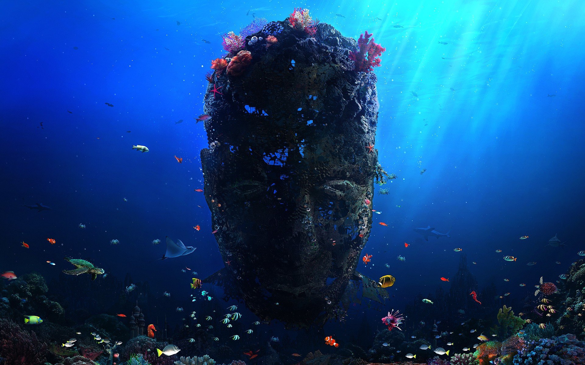 HD PC desktop wallpaper showing a fantasy underwater scene with a giant ancient stone face surrounded by colorful fish and ocean life.