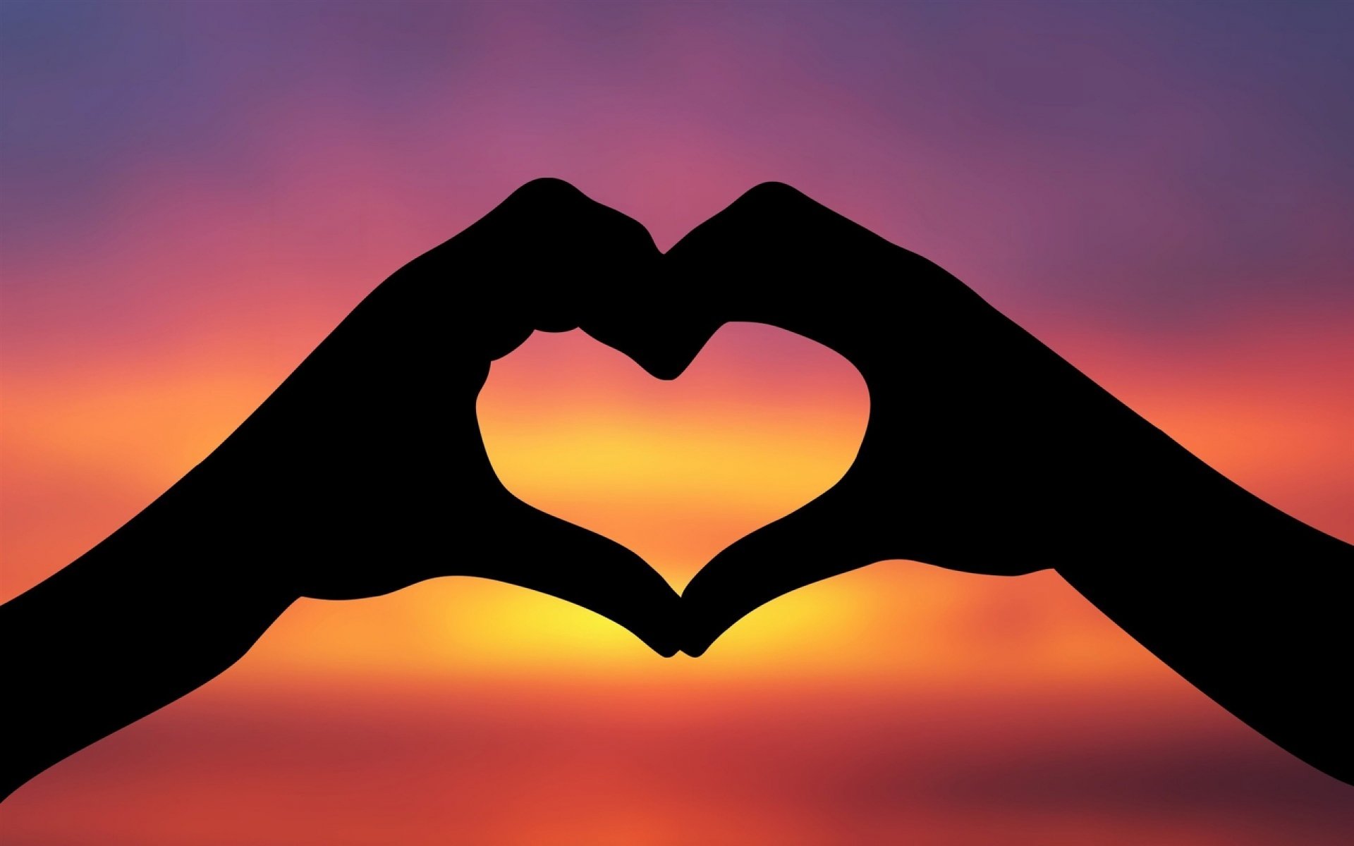Silhouetted hands create a heart shape against a vibrant sunset, embodying love and connection in this beautiful HD desktop wallpaper.