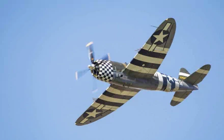 HD PC desktop wallpaper featuring a vintage military aircraft with black and yellow stripes flying against a clear blue sky.