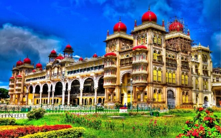 HD desktop wallpaper featuring a majestic man-made palace with red domes and intricate architecture, set against a vibrant blue sky and surrounded by lush gardens.