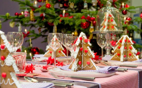 HD holiday wallpaper featuring a festive Christmas table setting with glassware, gingerbread houses, and candy canes in front of a decorated Christmas tree.