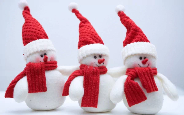 Three cheerful snowmen wearing red Santa hats and matching scarves, embodying the holiday spirit. This festive image makes a vibrant Christmas desktop wallpaper.