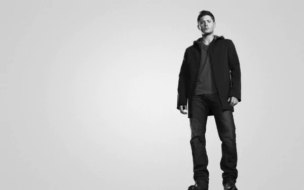 A striking black-and-white HD wallpaper featuring Jensen Ackles, standing confidently against a minimalist background, showcasing his charismatic presence.