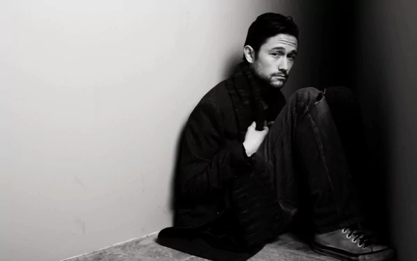 Monochrome HD desktop wallpaper featuring a pensive man sitting on the floor against a wall, embodying a subdued atmosphere.