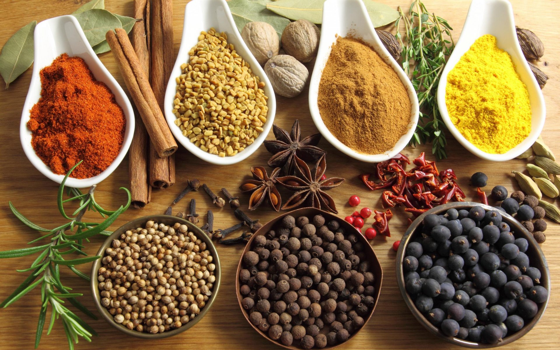 Vibrant assortment of herbs and spices displayed in bowls and spoons on a wooden surface, captured in HD for a rich PC desktop wallpaper background.