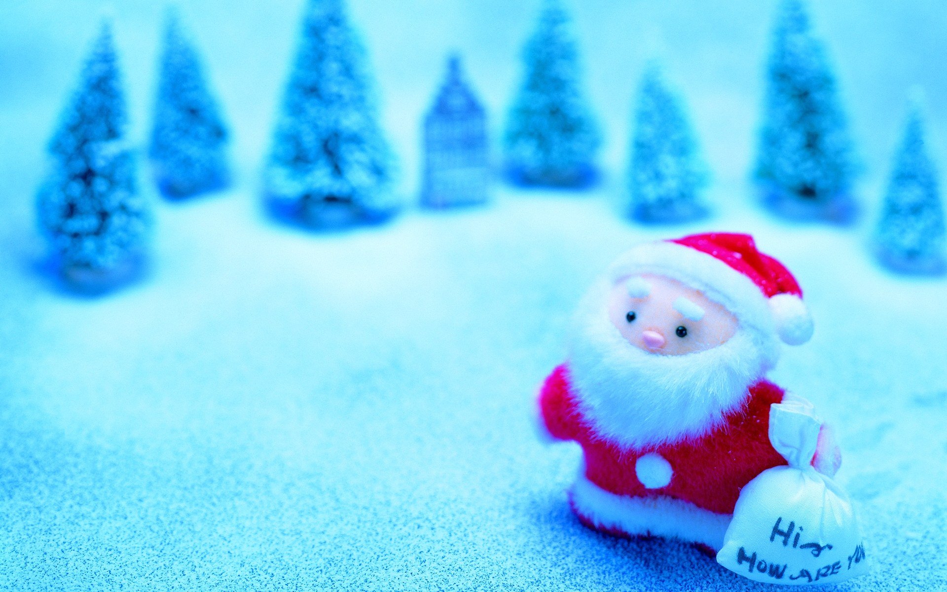 HD PC desktop wallpaper featuring a cute Santa Claus figure in snow with blurred trees in the background, capturing a festive holiday and Christmas spirit.