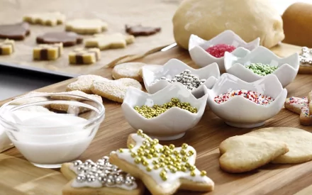 HD PC desktop wallpaper showing a wooden board with star-shaped biscuits being decorated with colorful sprinkles and a bowl of white icing nearby.