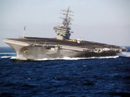 HD desktop wallpaper featuring the USS Ronald Reagan (CVN-76), a powerful aircraft carrier warship navigating the open sea.