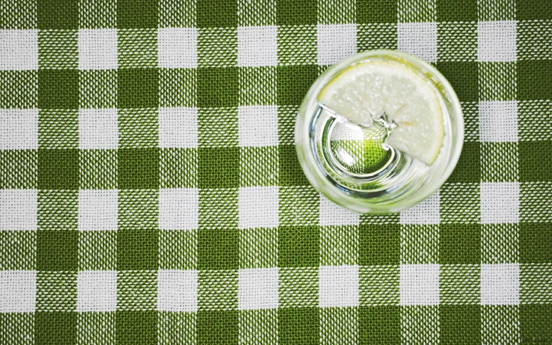 HD desktop wallpaper featuring a top-down view of a glass of lemon water on a green and white checkered tablecloth.