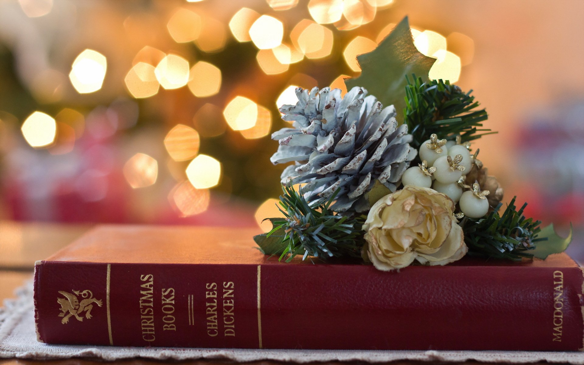 Still life photography featuring a festive arrangement with pinecones and flowers on a red book, captured in HD for a PC desktop wallpaper background.