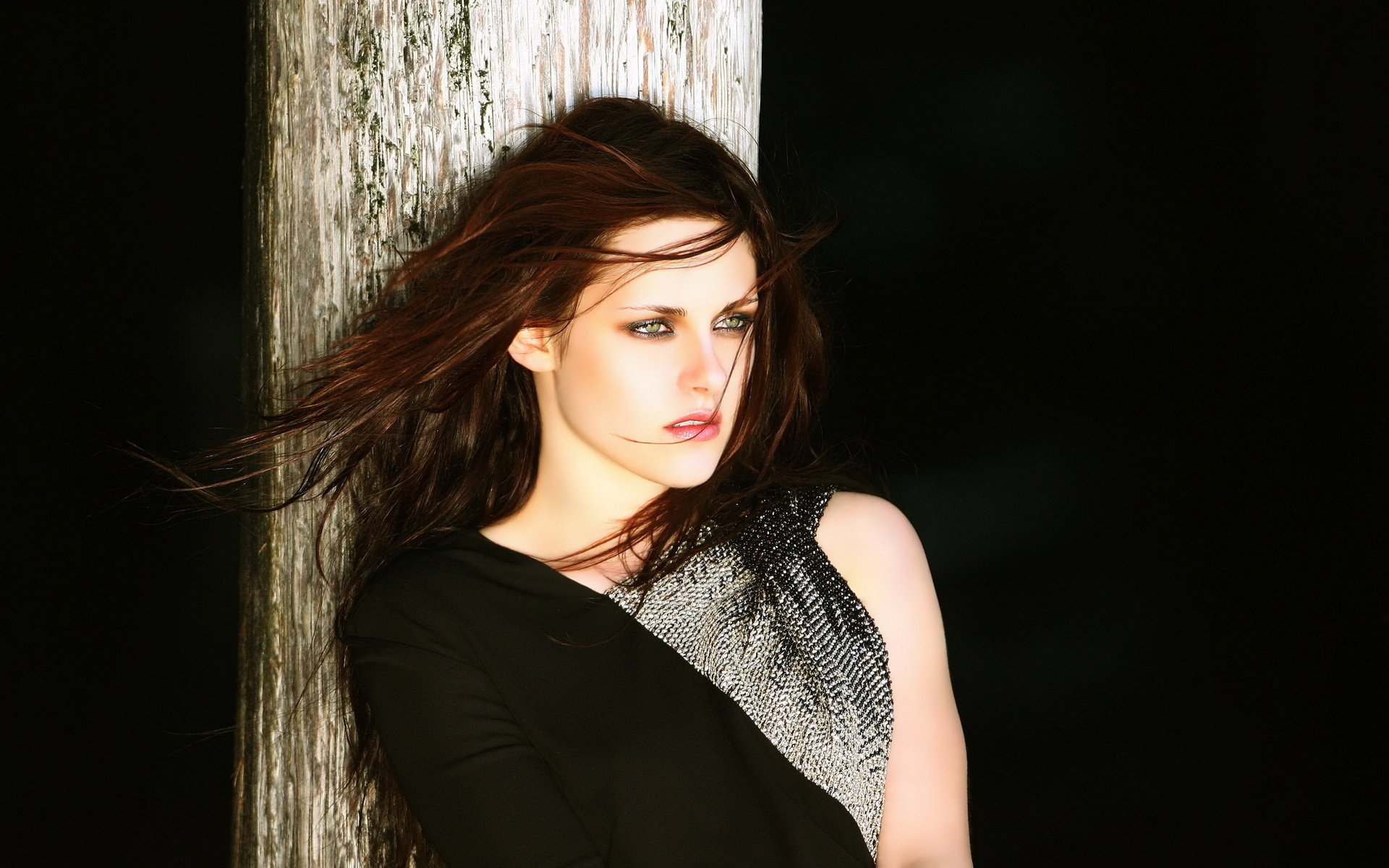 A striking HD wallpaper featuring American actress Kristen Stewart, showcasing her intense gaze and flowing hair against a dark background, exuding a sense of mystery and elegance.