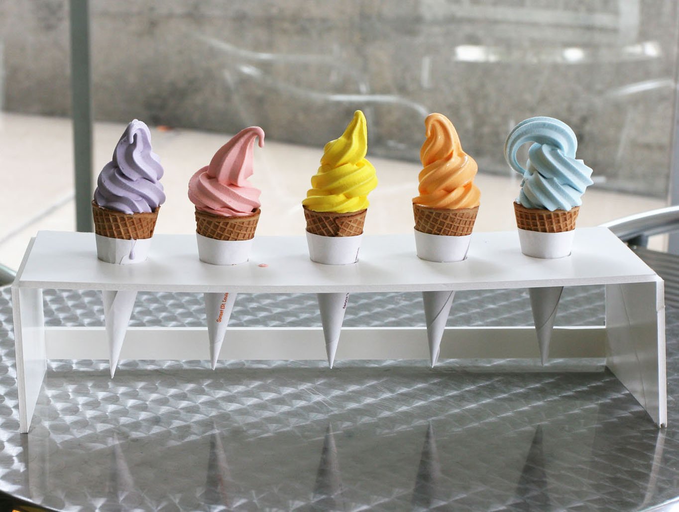 HD PC desktop wallpaper featuring five colorful soft-serve ice cream cones in a row, each in a small cone holder with flavors in pastel purple, pink, yellow, orange, and blue.