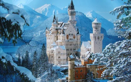 Snow-covered Neuschwanstein Castle stands majestically against a backdrop of blue sky and snowy mountains, captured in an HD PC desktop wallpaper.