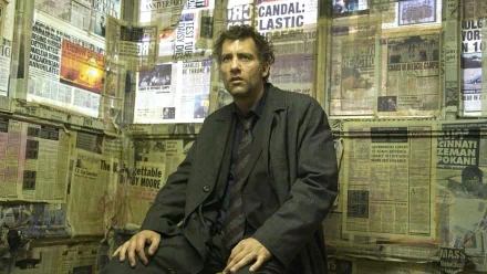 HD desktop wallpaper featuring Clive Owen in Children Of Men, sitting in a room papered with chaotic news clippings.
