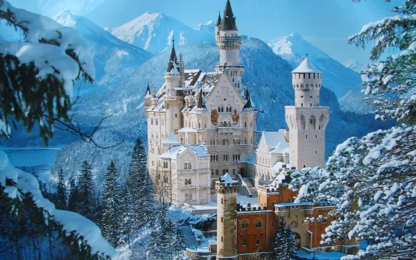 Snow-covered Neuschwanstein Castle stands majestically against a backdrop of blue sky and snowy mountains, captured in an HD PC desktop wallpaper.