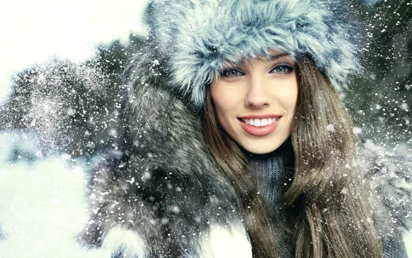A beautiful woman smiles warmly, wearing a soft fur hat and a cozy coat, surrounded by falling snow, creating a serene winter scene in this 4K Ultra HD desktop wallpaper.