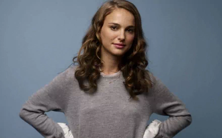 HD desktop wallpaper featuring celebrity Natalie Portman posing against a solid blue background with a relaxed, confident expression.