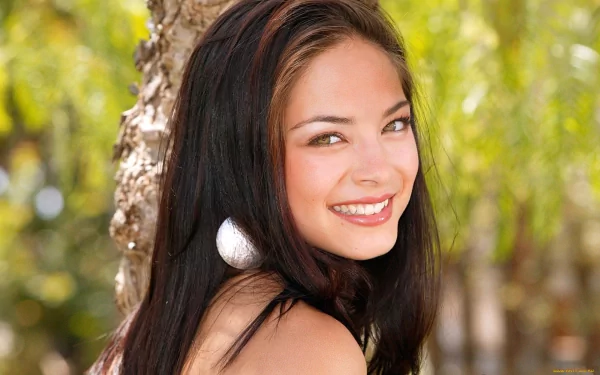 HD PC desktop wallpaper featuring celebrity Kristin Kreuk smiling outdoors with a blurred natural background.
