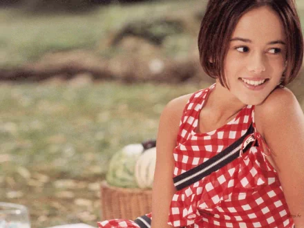 HD PC desktop wallpaper featuring Alizée smiling outdoors with a soft-focus natural background, reflecting a serene and musical atmosphere.