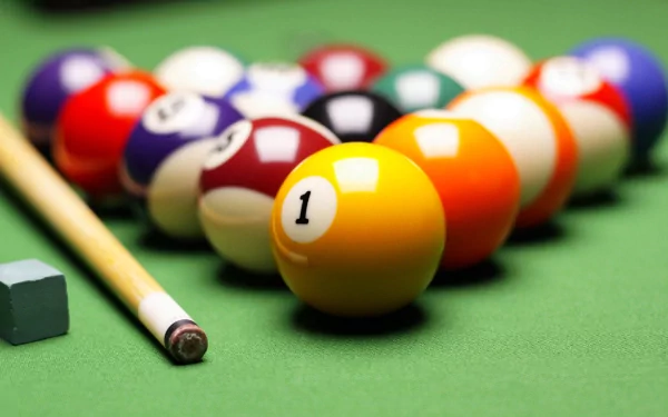 A vibrant image of a pool table with colorful billiard balls arranged and a cue stick resting nearby, this HD desktop wallpaper brings the excitement of the game to your screen.