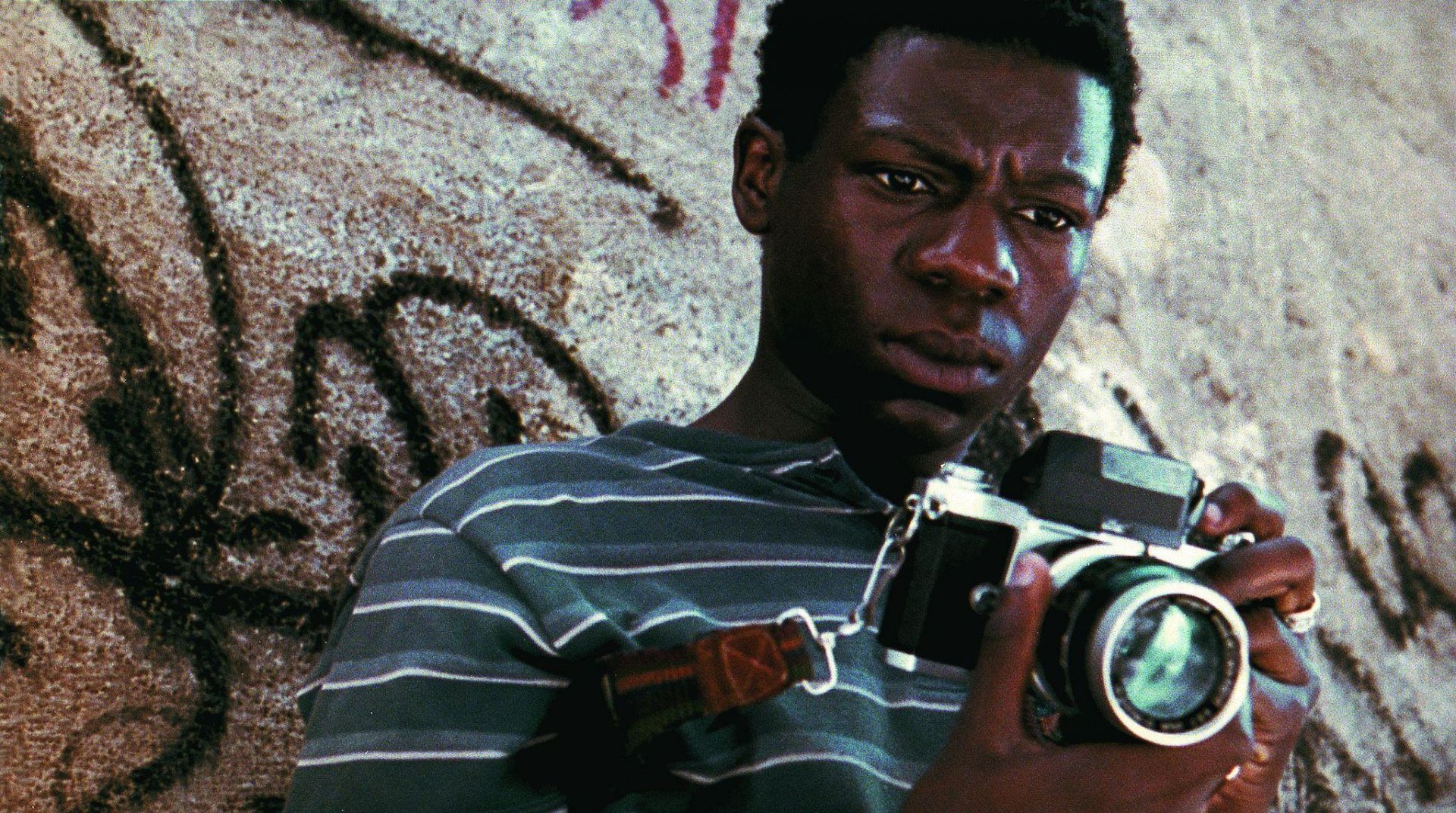 HD wallpaper of a scene from City of God with a person holding a camera, evoking the film's intense atmosphere.