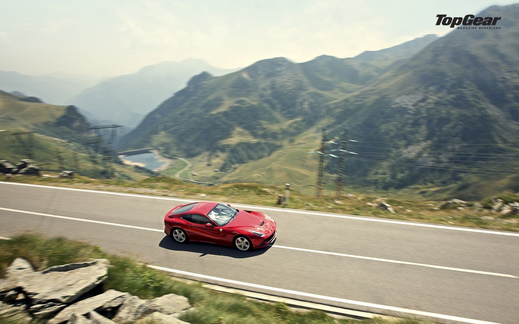 HD desktop wallpaper featuring a red Ferrari F12berlinetta driving on a mountainous road with scenic views.