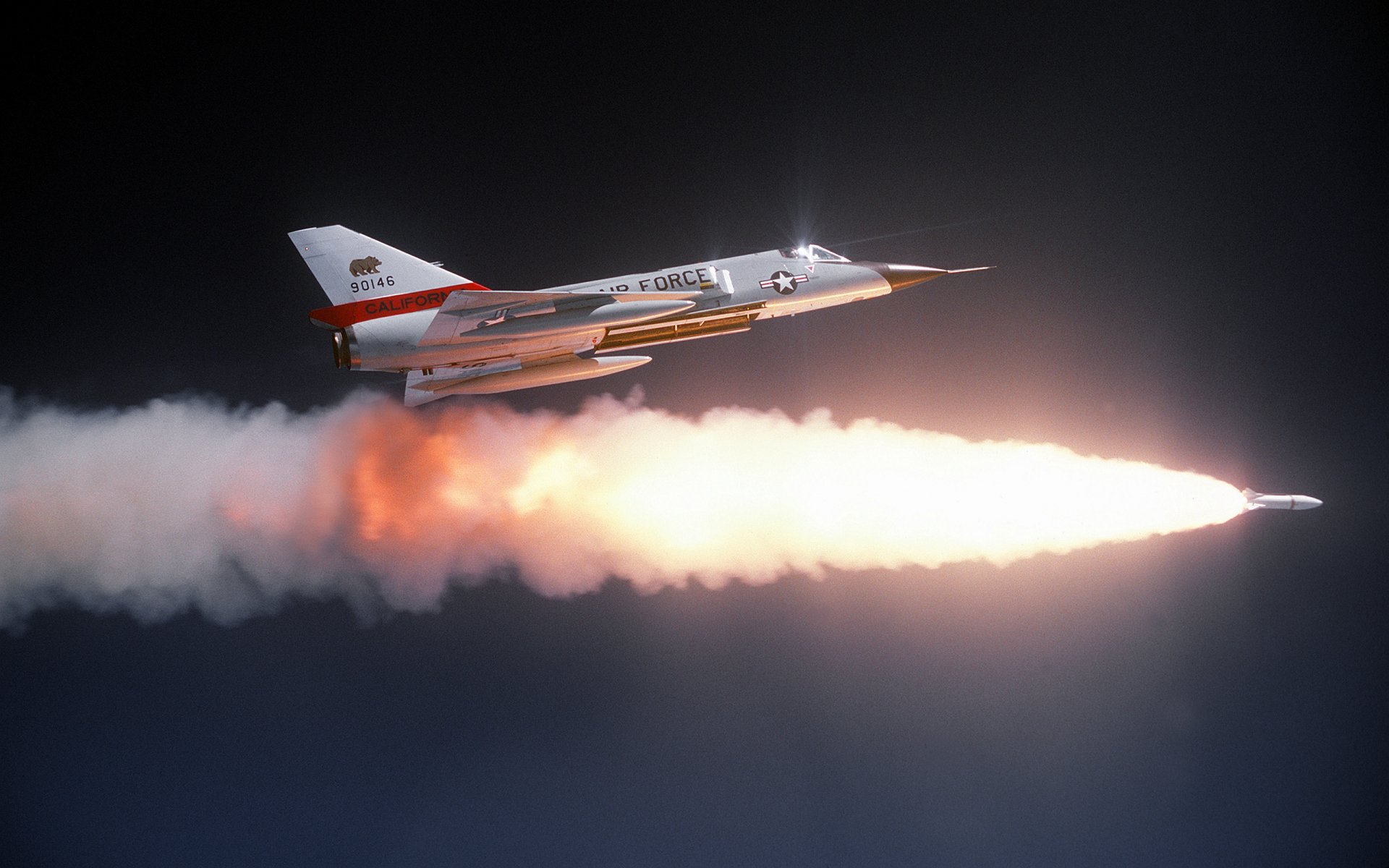 Convair F-106 Delta Dart military jet firing a rocket with a bright plume across a dark sky — 2K Quad HD PC desktop wallpaper background
