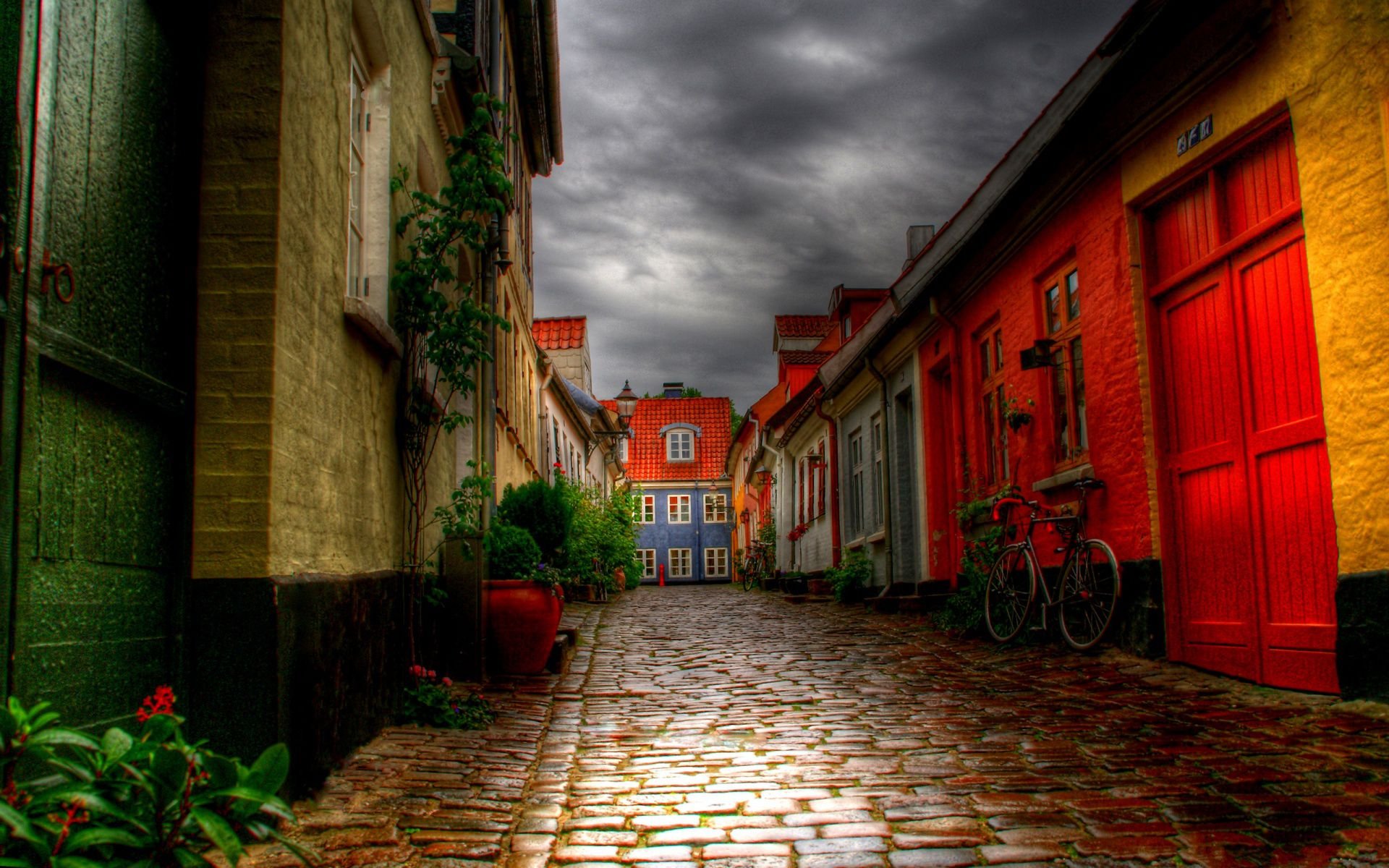 A vibrant alleyway in a quaint town, showcasing colorful buildings and a cobblestone path under a dramatic sky. This stunning HDR photography makes for a captivating desktop wallpaper.