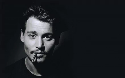 A striking black-and-white HD wallpaper featuring Johnny Depp, showcasing his charismatic presence with a cigarette in his mouth against a dark background.