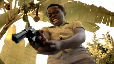 HD wallpaper of a scene from City of God featuring a person exuberantly pointing a gun, with a blurred natural background.