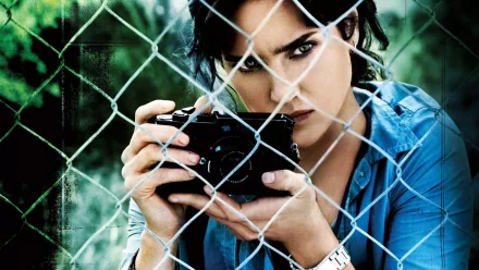 HD desktop wallpaper featuring Jennifer Connelly from Blood Diamond, intensely focusing through a camera, behind a chain-link fence.