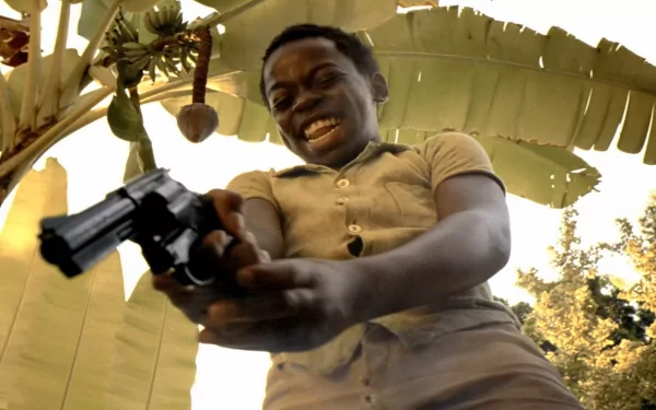 HD wallpaper of a scene from City of God featuring a person exuberantly pointing a gun, with a blurred natural background.
