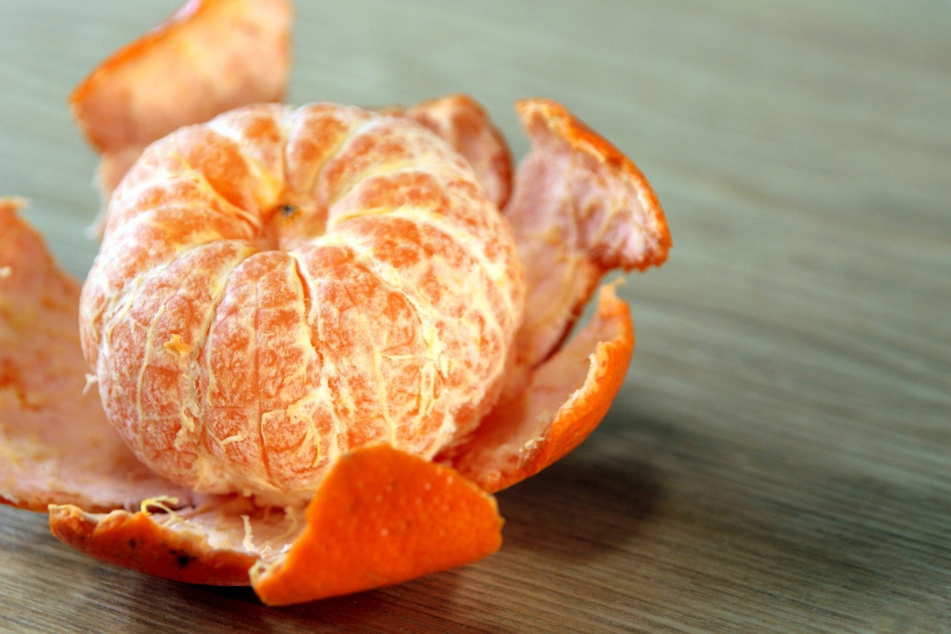 HD PC desktop wallpaper featuring a close-up of a peeled mandarin with vibrant orange skin against a wooden surface.