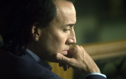Close-up HD desktop wallpaper of celebrity Nicolas Cage deep in thought, showcasing a contemplative side profile with muted background tones.