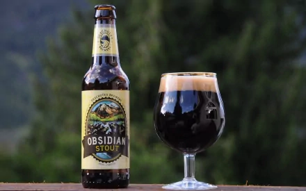 HD desktop wallpaper featuring a bottle of Obsidian Stout beer beside a filled stout glass with a blurred natural background.