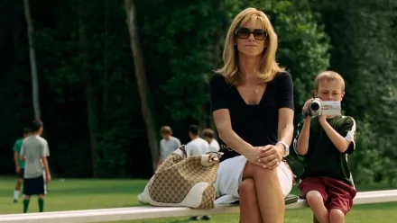 HD desktop wallpaper featuring Sandra Bullock from the movie The Blind Side, sitting outdoors with a young boy filming beside her.